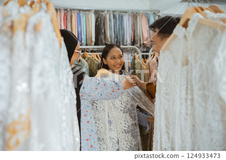 A group of friends happily selecting beautiful and stylish dresses at a boutique A group of friends happily selecting beautiful and stylish dresses at a boutique 124933473