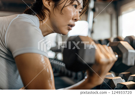 Woman Lifting Weights in a Gym, Focusing on Strength Training and Fitness 124933720