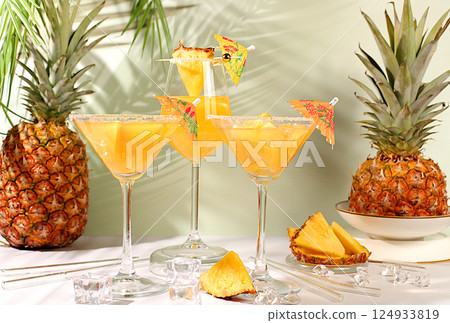 Summer party concept. Lemonade royal cocktail, martini or punch made of tequila, rum and vodka with pineapple slices, orange, ice. Diet drink for advertising a bar or cafe, restaurant menu. Summer party concept. Lemonade royal cocktail, martini or punch made of tequila, rum and vodka with pineapple slices, orange, ice. Diet drink for advertising a bar or cafe, restaurant menu. 124933819