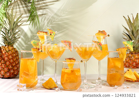Various alcoholic drinks with pineapple for bar advertising. Lemonade royal cocktail, martini, margarita and punch from tequila, rum and vodka with slices of pineapple, ice. Summer party concept. 124933821