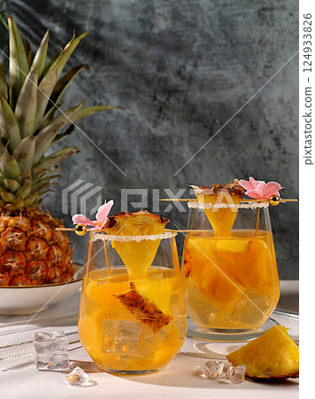 Refreshing summer diet drink recipe,Cold homemade cocktail or lemonade with pineapple, orange, ice on sunny kitchen table,Detox diet and summer party concept.restaurant menu,selective approach 124933826