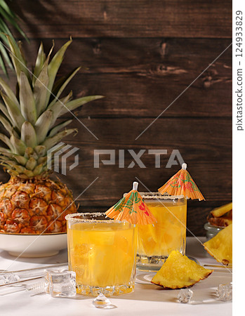 Homemade cocktail or lemonade with pineapple, orange, ice on sunny kitchen table. Refreshing summer diet drink recipe, Detox diet and summer party concept. Restaurant menu, selective approach 124933829