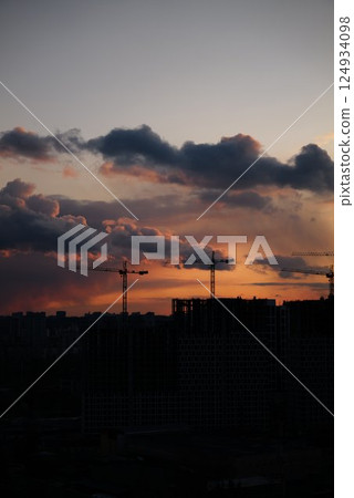 Construction cranes silhouetted against a colorful sunset in the city Construction cranes silhouetted against a colorful sunset in the city 124934098
