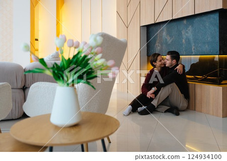 Couple enjoying intimate moment in modern living room with fireplace 124934100