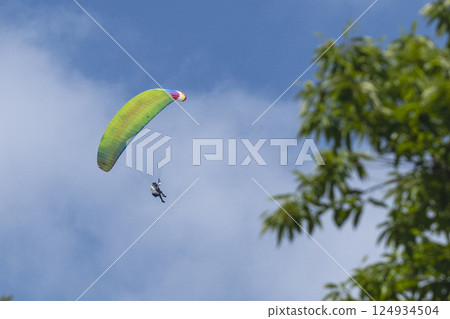 A paraglider flying in the clear blue sky 124934504