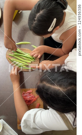 Two brunettes girls are preparing fresh cucumber slices and salmon for a healthy meal Two brunettes girls are preparing fresh cucumber slices and salmon for a healthy meal 124936386