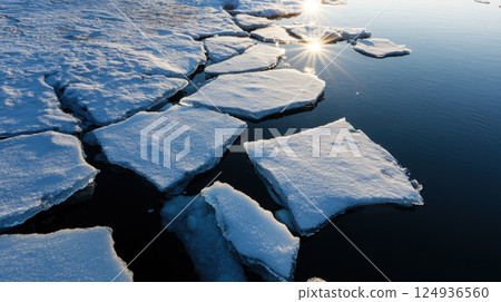 Melting icebergs with sunlight reflecting on water create serene scene 124936560