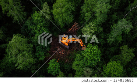 massive bulldozer clearing trees in dense forest, creating path 124936695