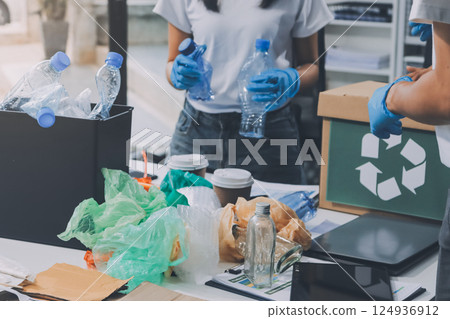 Close-up of female hands from a family collecting plastic waste and bottles from the ground. They wear gloves and focus on recycling to help reduce plastic pollution and protect the environment. Close-up of female hands from a family collecting plastic waste and bottles from the ground. They wear gloves and focus on recycling to help reduce plastic pollution and protect the environment. 124936912