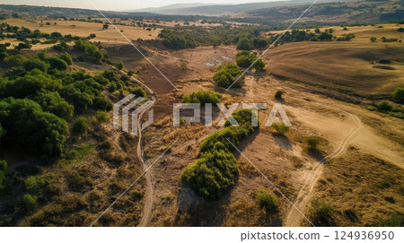 Drought affected landscape with dry terrain and sparse vegetation 124936950