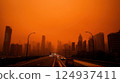 dystopian city skyline shrouded in orange haze, showcasing pollution 124937411