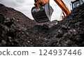 Excavator digging through dark soil, revealing layers of earth and rock 124937446