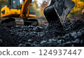 Excavator digging through dark soil, revealing layers of earth and gravel 124937447