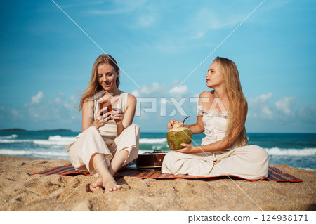Spending a Relaxing Beach Day with Friends while Enjoying Refreshing Coconut Water by the Ocean Spending a Relaxing Beach Day with Friends while Enjoying Refreshing Coconut Water by the Ocean 124938171