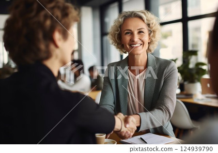 Joyful Senior Businesswoman Sealing a Contract with a Handshake at Office Meeting. Generative ai 124939790