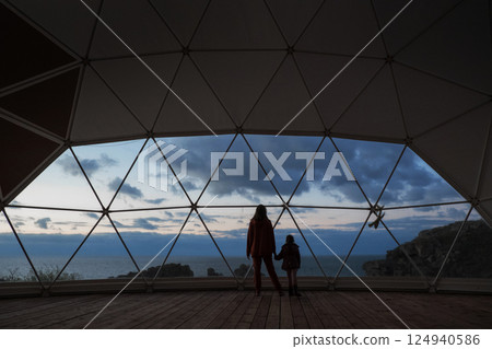 A woman with a child looks at a beautiful sunset. A vacation with incredible views of the sea and mountains. High quality photo 124940586