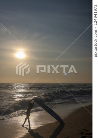 Silhouette of a Surfer Riding Waves at Sunset on the Beach, Full of Vibrant Colors 124941972