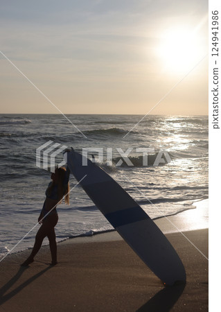 Silhouette of a Surfer Riding Waves at Sunset on the Beach, Full of Vibrant Colors Silhouette of a Surfer Riding Waves at Sunset on the Beach, Full of Vibrant Colors 124941986