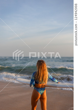 Surfer Ready to Ride the Thrilling Waves at Sunset, Embracing the Beauty of Nature Surfer Ready to Ride the Thrilling Waves at Sunset, Embracing the Beauty of Nature 124942008