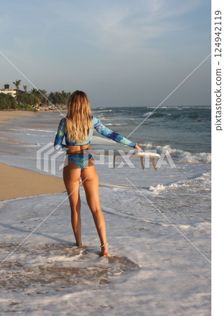 A Surfer Eagerly Prepared to Ride the Cresting Waves on a Stunningly Beautiful Beachside 124942119
