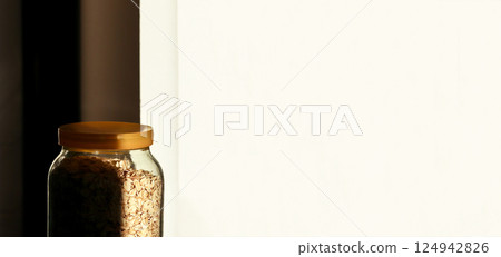 A minimalistic scene featuring a jar of oatmeal against a clean white background, with subtle shadows adding depth to the composition. Banner for design with copy space A minimalistic scene featuring a jar of oatmeal against a clean white background, with subtle shadows adding depth to the composition. Banner for design with copy space 124942826