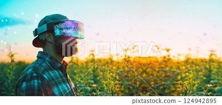 A male farmer standing in a field wearing a VR headset, symbolizing the fusion of traditional agriculture and modern technology. agri-tech, sustainable development A male farmer standing in a field wearing a VR headset, symbolizing the fusion of traditional agriculture and modern technology. agri-tech, sustainable development 124942895