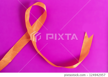 Orange ribbon on a bright pink background representing awareness and support efforts. 124942957