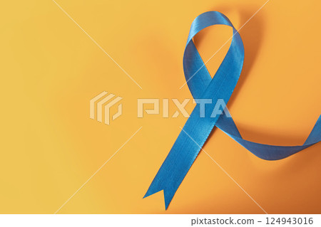 Blue awareness ribbon on a vibrant yellow background represents support and care. 124943016