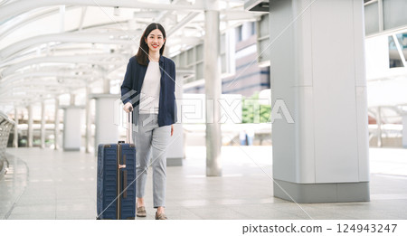 Adult business asian woman walking with luggage for work and travel at station platform on day 124943247