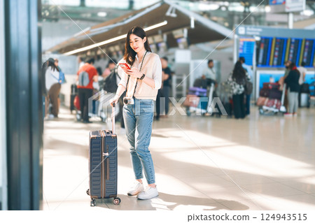 Portrait of standing tourist woman passenger at international airport terminal for holidays travel Portrait of standing tourist woman passenger at international airport terminal for holidays travel 124943515
