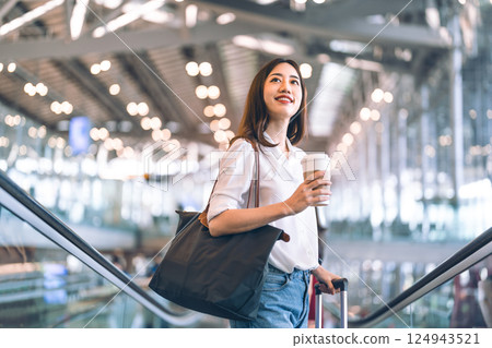 Adult passenger business asian woman with coffee cup and luggage at airport terminal for depature Adult passenger business asian woman with coffee cup and luggage at airport terminal for depature 124943521