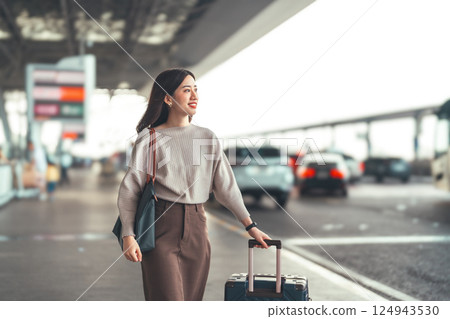 Standing tourist woman with travel luggage waiting at bus terminal for transport on day 124943530