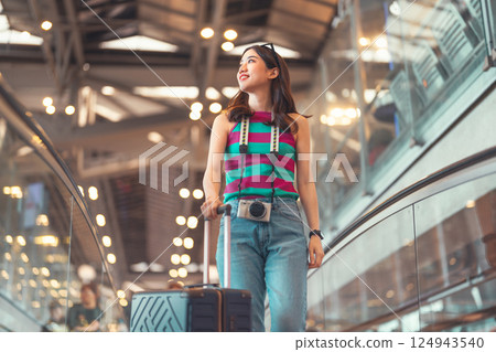 Passenger woman to transit with travel luggage and camera at international airport journey holidays Passenger woman to transit with travel luggage and camera at international airport journey holidays 124943540