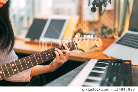 Young asian woman composer playing guitar music with digital technology at home studio 124943956