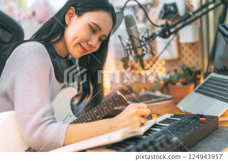 Young asian woman composer playing guitar music with digital technology at home studio 124943957