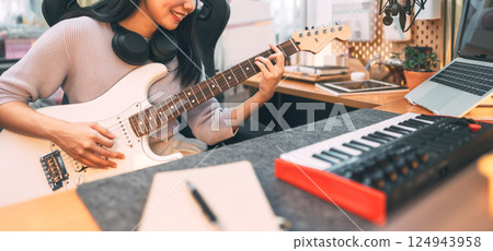 Young asian woman composer playing guitar music with digital technology at home studio 124943958