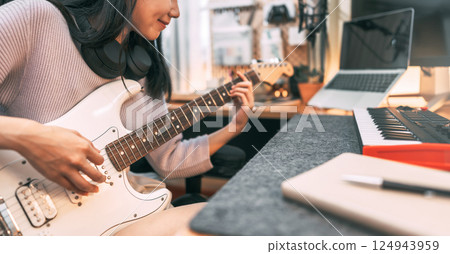 Young asian woman composer playing guitar music with digital technology at home studio 124943959