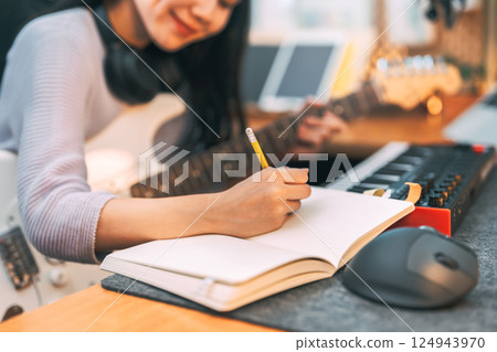 Young asian woman composer playing guitar music with digital technology at home studio 124943970