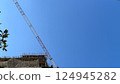 View of tall construction crane and upper part of building with scaffolding  124945282