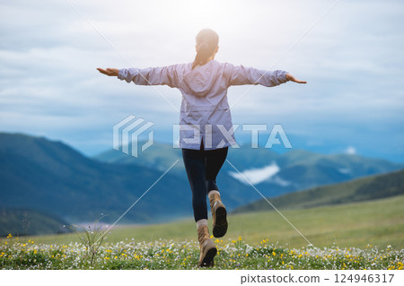 Woman hiker on beautiful flowering grassland mountain top Woman hiker on beautiful flowering grassland mountain top 124946317