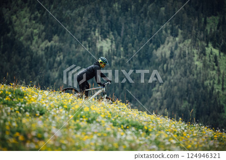 Riding mountain bike on flowering grassland mountain top Riding mountain bike on flowering grassland mountain top 124946321