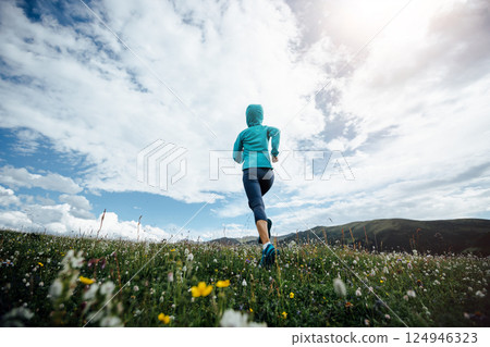 Fitness woman runner running at flowering grassland mountain top Fitness woman runner running at flowering grassland mountain top 124946323