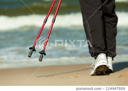 Nordic walking. Female legs hiking on the beach. 124947889