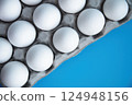 Fresh White Eggs Neatly Arranged in Gray Carton Tray top view, against striking Blue Backdrop. Purity and Freshness grocery, ideal for culinary themes, breakfast concepts, foodrelated organic designs 124948156