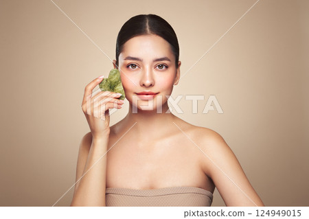 Young woman doing scrapping massage facial skin Young woman doing scrapping massage facial skin 124949015