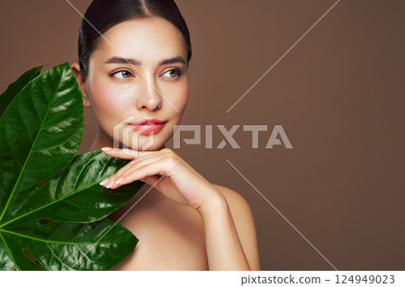 Close up woman face with green exotic leaf Close up woman face with green exotic leaf 124949023