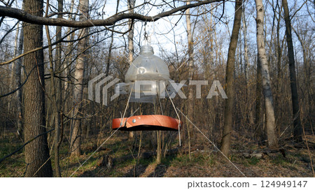 A creative bird feeder crafted from a plastic bottle hangs from a tree branch in a quiet forest. The feeder invites local birds, enhancing the natural environment during the day. A creative bird feeder crafted from a plastic bottle hangs from a tree branch in a quiet forest. The feeder invites local birds, enhancing the natural environment during the day. 124949147