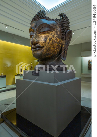 Large bronze head of Buddha with gold remnants exhibited at National Museum Bangkok, Showcasing Thai spiritual artistry and historic craftsmanship 124949584