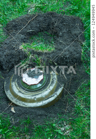 Green anti tank mine on the grass in the ground. 124949945