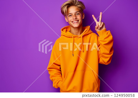 A young man in an orange hoodie making a peace sign with his hand A young man in an orange hoodie making a peace sign with his hand 124950058